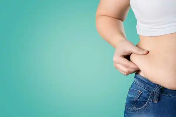 Image of woman pinching her love handles to show weight gain Tilehurst