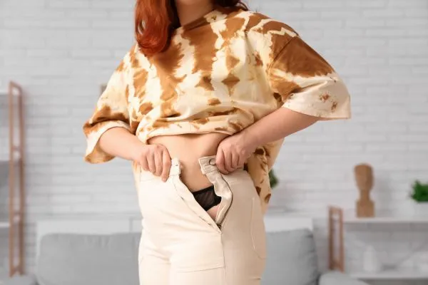 Image of woman trying to do her trousers up after pregnancy weight gain Tilehurst